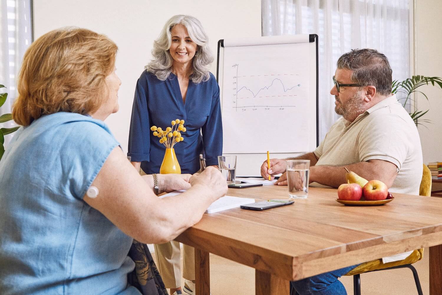 Eine Frau erklärt zwei Personen mit Diabetes etwas. Beide machen sich Notizen.