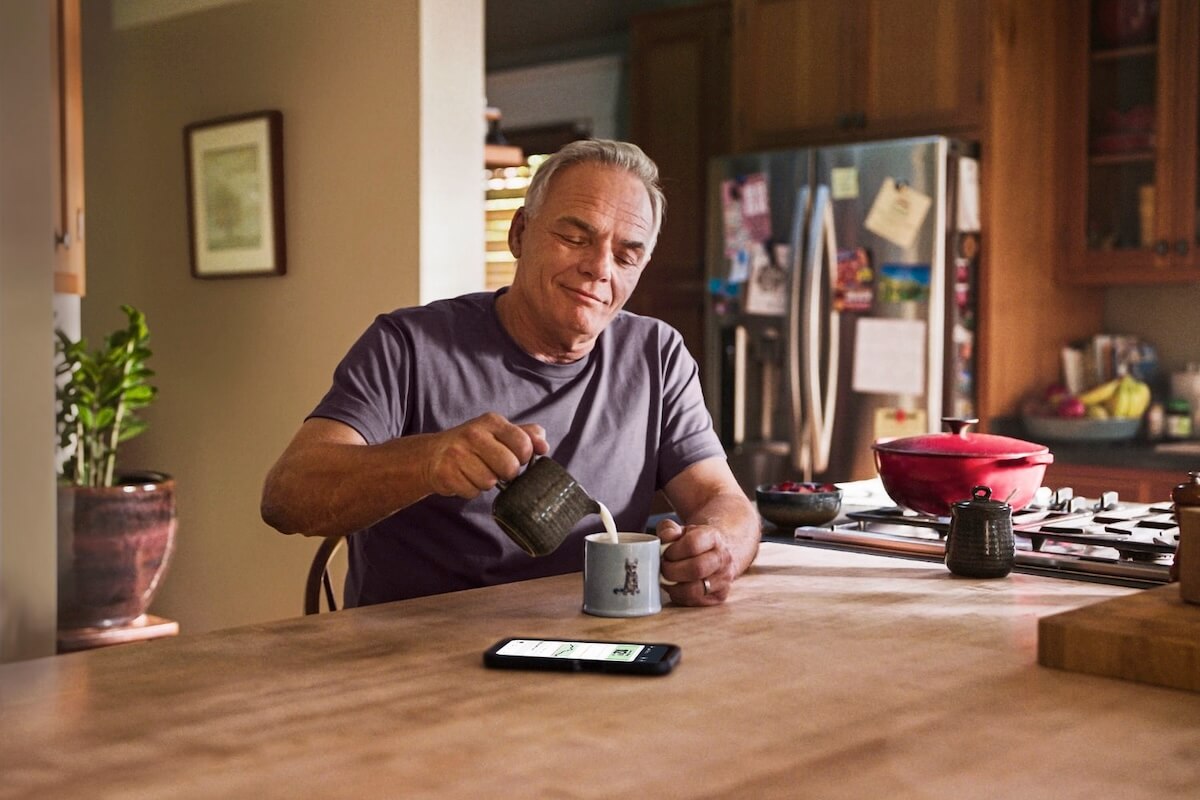 Diabetiker trinkt Kaffee. Smartphone mit FreeStyle Libre App liegt auf dem Tisch vor ihm.