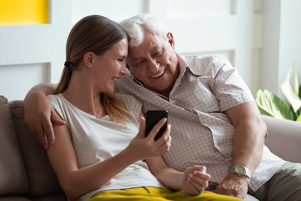 Tochter und Vater schauen gemeinsam in die LibreLinkUp App um den aktuellen Glukosewert des Vaters abzulesen