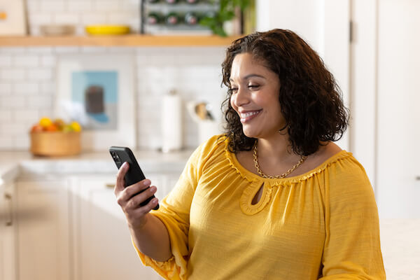 Eine Frau mittleren Alters schaut auf Ihr Smartphone um den aktuellen Glukosewert ihres Kindes in der LibreLinkUp App abzulesen