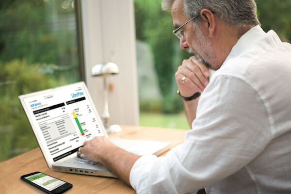 Mann sitzt vor einem Computer und schaut sich LibreView Berichte an