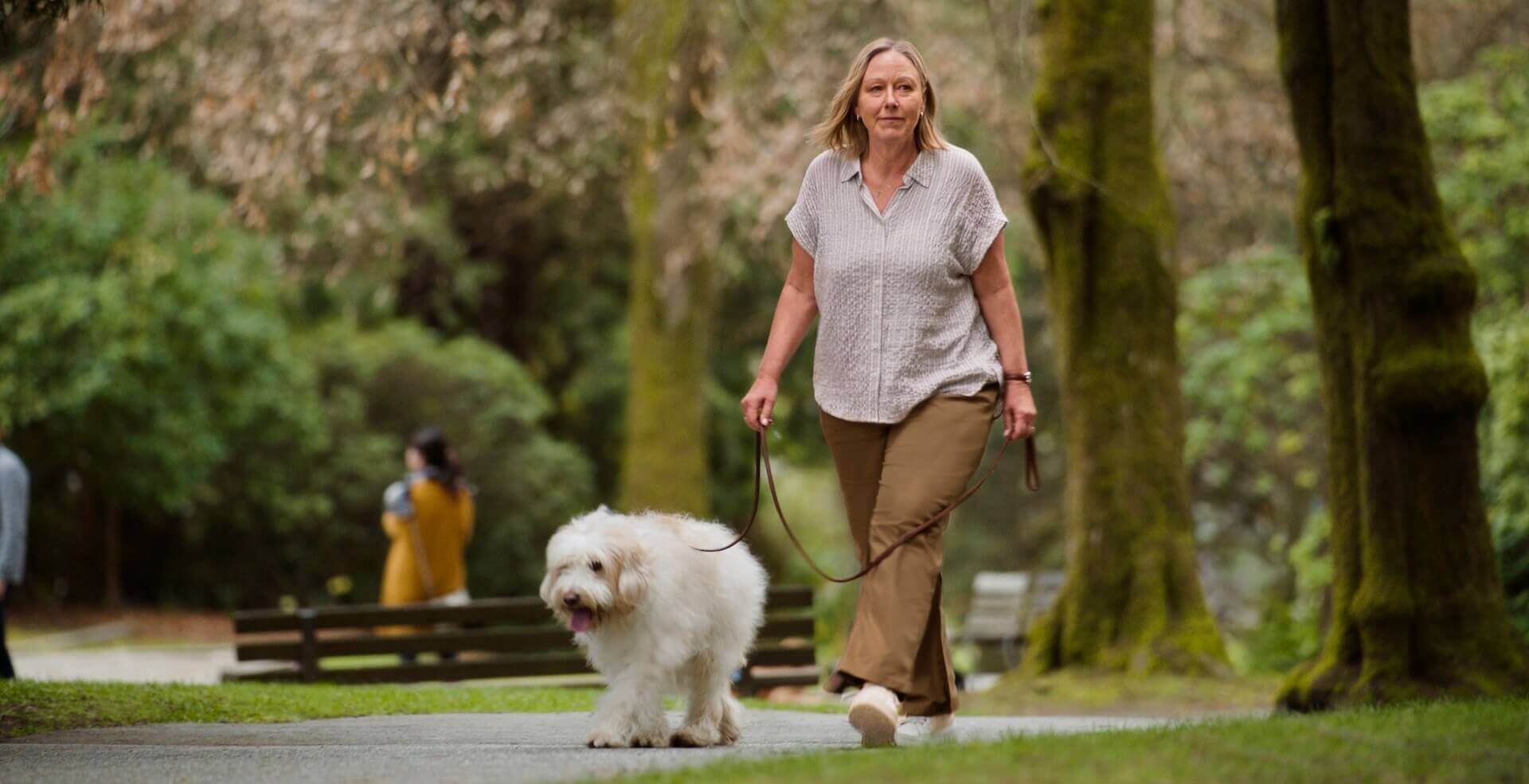 Frau mit Diabetes geht mit ihrem Hund im Park spazieren